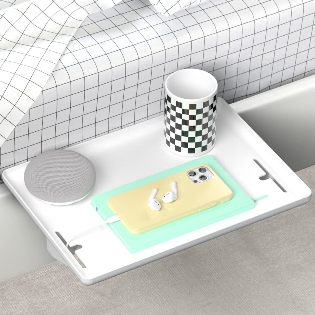 White shelf holding mug and cell phone attached to bed frame