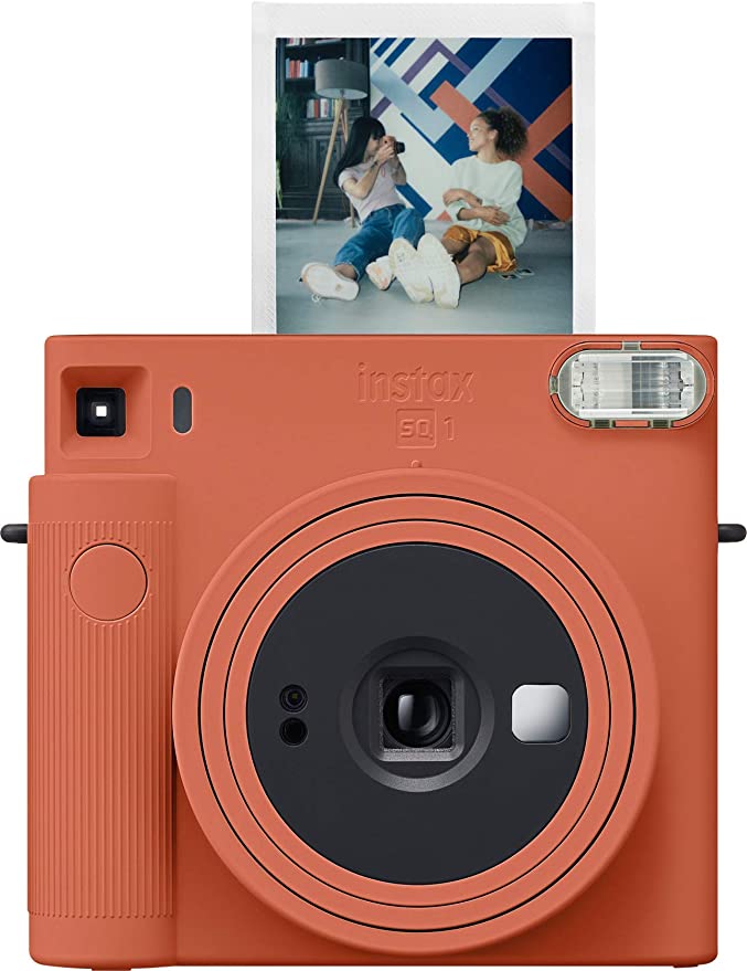 Terracotta colored instant camera with film photo sticking out the top
