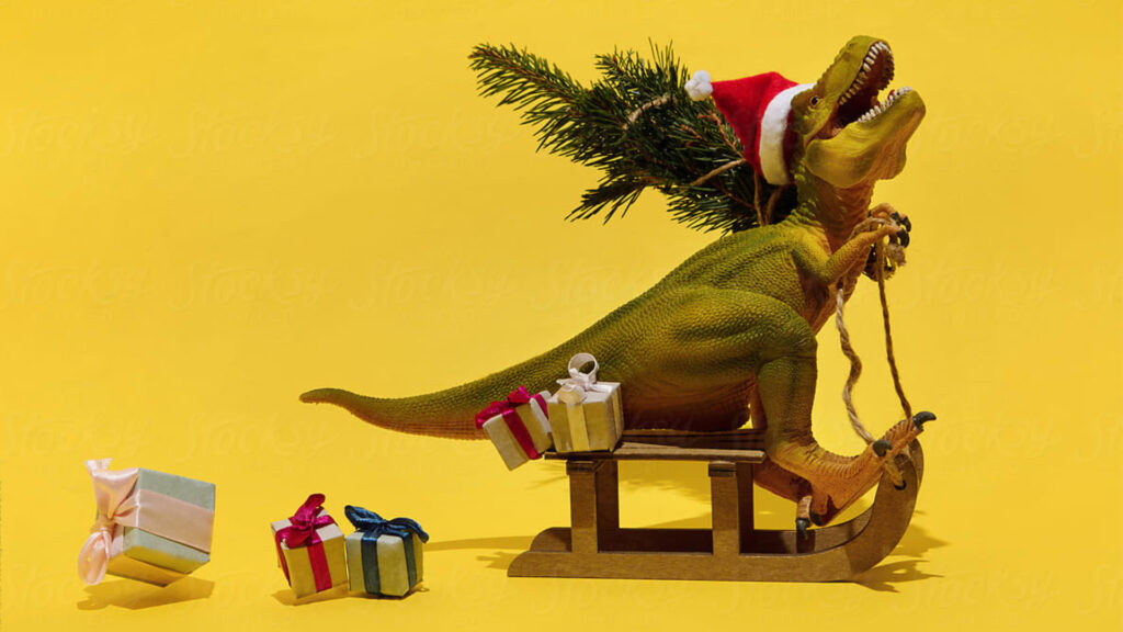 Toy dinosaur wearing a Santa hat riding on a sleigh with gifts